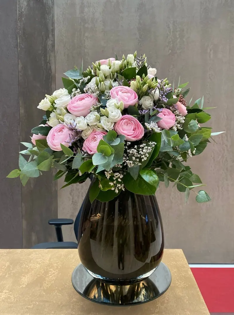 Bouquet de roses et renoncules roses dans un vase noir, pour l'accueil d'un hôtel