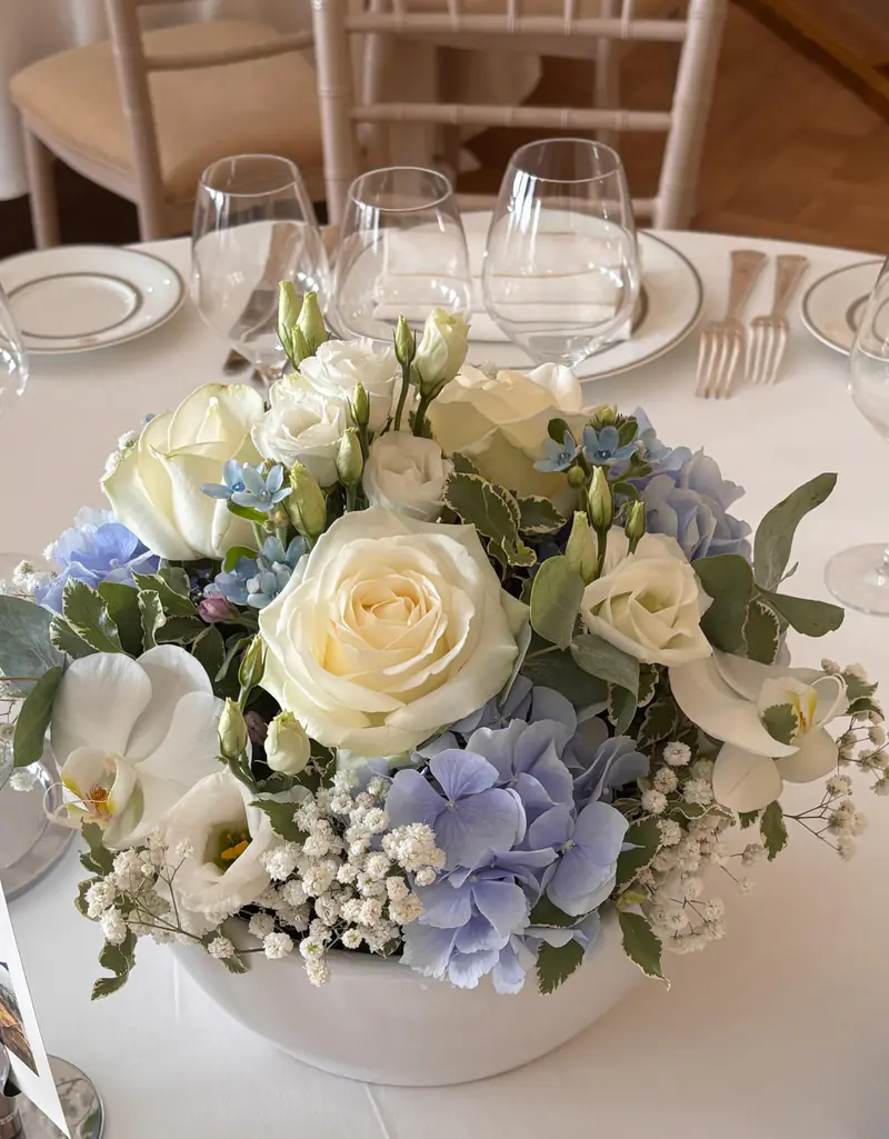 Centre de table de mariage en roses blanches, hortensias bleus et gypsophile