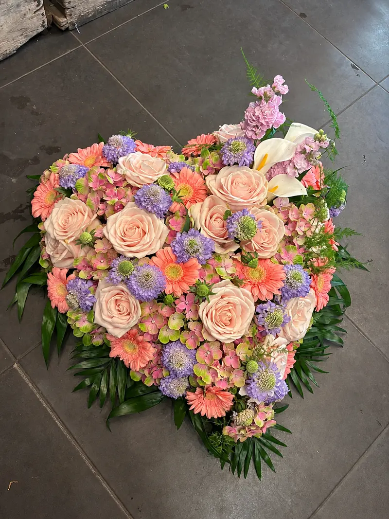 Cœur de deuil en roses pêche, gerberas et fleurs mauves