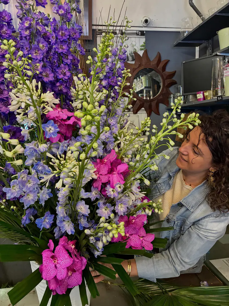 Fleuriste de Fleurs d'Italie présentant une composition de delphiniums à l'atelier