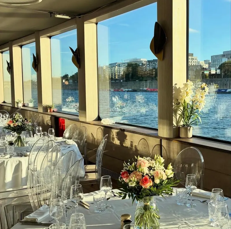 Table dressée et bouquets sur une péniche, face à la Seine